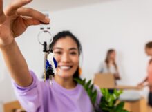 Portrait of young woman holding a potted plant and the keys to her new home