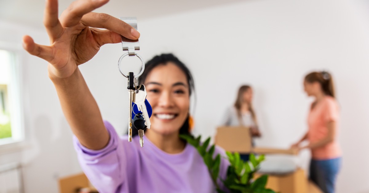Portrait of young woman holding a potted plant and the keys to her new home
