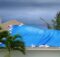 A dark sky and blowing trees indicate a storm coming, and a roof with a blue tarp partially covering an area, held by sandbags.