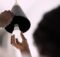 A woman holds the edge of an overhead pendant light fixture as she prepares to install a new LED light bulb.